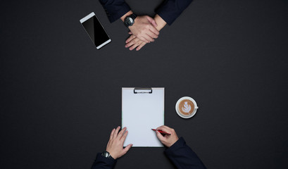 Businessman hands sign on blank agreement with client. Flat lay and top view with copy space on black background .business desk lifestyle concept.