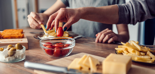 Obraz na płótnie Canvas Woman taking cherry tomato from a dish on table