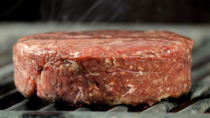 cooking raw burgers cutlet on hot grill with flames