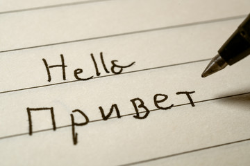 Beginner Russian language learner writing Hello word in Russian cyrillic alphabet on a notebook
