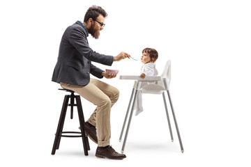 Father sitting and feeding his baby in a feeding