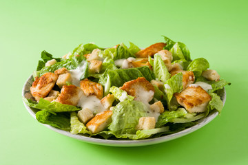 Caesar salad with lettuce,chicken and croutons on green background. Copyspace