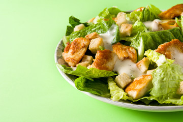 Caesar salad with lettuce,chicken and croutons on green background. Copyspace