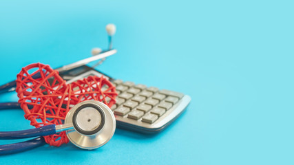 red heart and calculator with stethoscope isolated on blue background. tax offset concept. Medical...
