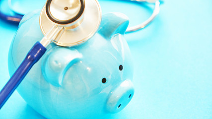 piggy bank and stethoscope on blue background, concept of medical expenses. bankrupt resuscitation