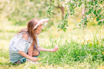 Naklejka na ściany i meble Adorable little girl in blooming apple garden on beautiful spring day