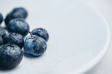 fresh blueberry berries on a white plate close-up. breakfast of wild berries. copy space
