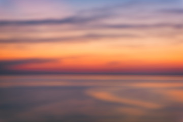 Blurred background of scenic sunset seascape with sea and amazing colorful cloudy sky, outdoor travel, motion blur