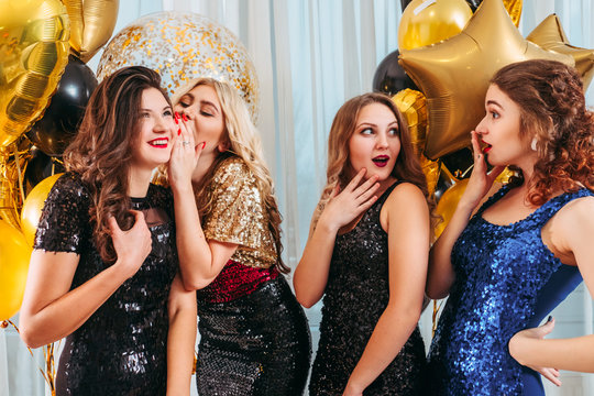 Girls party. Special occasion. Lady whispering intriguing, surprising news in her friend ear. Cusious young women.
