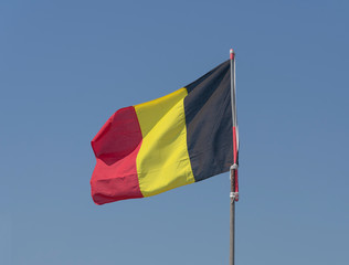Belgian flag waves in the wind with a nice blue sky as background