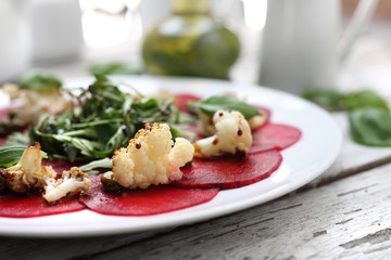 Vegetarian carpaccio of roasted beetroot with cauliflower and green salad.