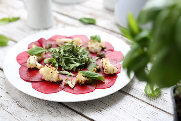 Vegetarian carpaccio of roasted beetroot with cauliflower and green salad.