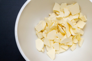 Pieces of butter are in a bowl for mixing in the preparation of cookies