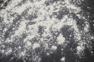 White flour is poured on a black table before cooking cookies