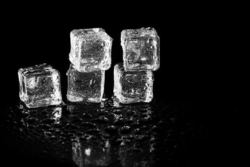 ice cubes reflection on black table background.