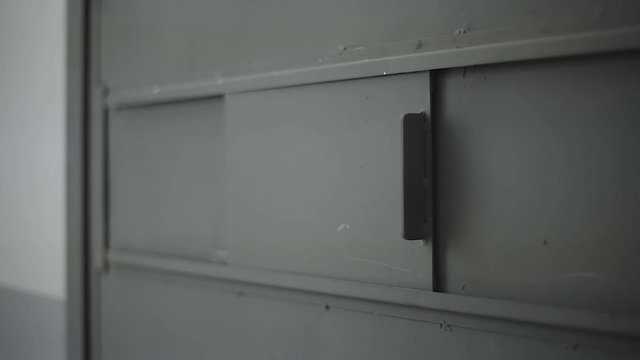 a prison cell door window open and close by hand
