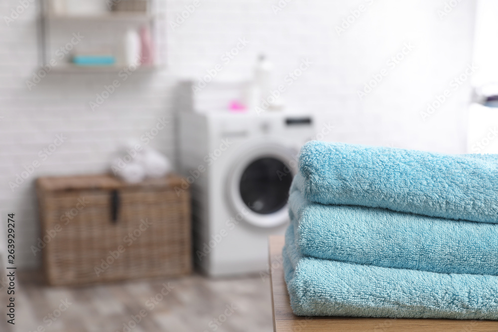 Poster Stack of towels on table against blurred background, space for text