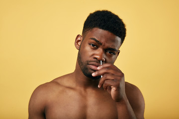 muscular man picks his nose with a cotton swab and looking at the camera, close up portrait, free...