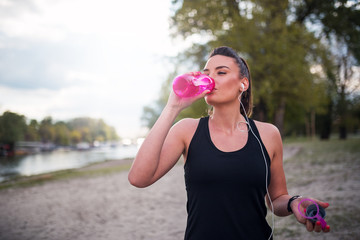 Fitness woman drinking water after running