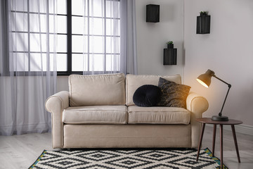 Comfortable couch near window in modern living room interior