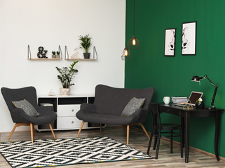 Modern living room interior with workplace near green wall