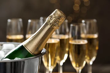 Fotobehang Bottle of champagne in bucket with ice and glasses on blurred background, closeup. Space for text © New Africa