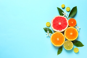 Flat lay composition with citrus fruits, leaves and flowers on color background. Space for text