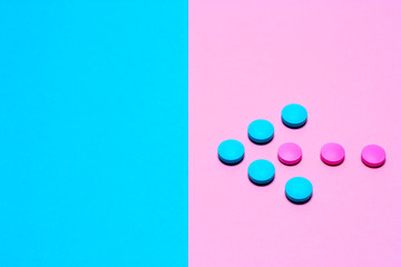 blue and pink tablets laid out in the form of an arrow on a paper background of blue and pink with copy space