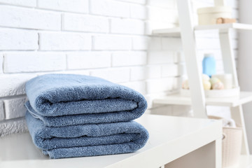 Stack of fresh towels on table in bathroom. Space for text