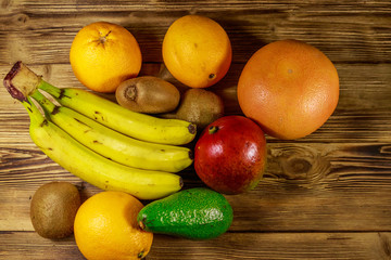 Assortment of tropical fruits on wooden table. Still life with bananas, mango, oranges, avocado, grapefruit and kiwi fruits