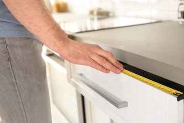 Obraz premium Man measuring kitchen furniture indoors, closeup. Construction tool