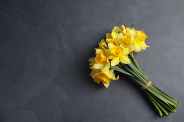 Bouquet of daffodils on dark background, top view with space for text. Fresh spring flowers