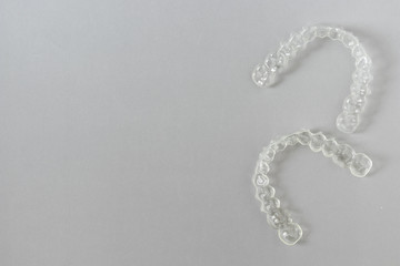 Top view of invisalign braces or invisible retainers on grey background, new orthodontic equipment