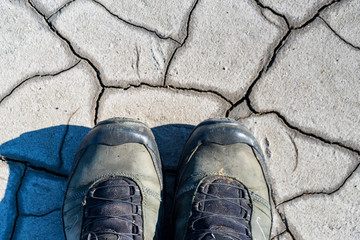 Top view hiking boots on dry muddy soil surface for background texture