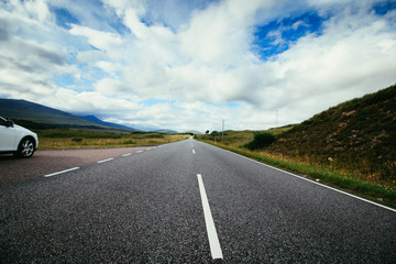 Fototapeta premium Trip or adventure: Abandoned, dramatic road in Scotland, cloudy sky.