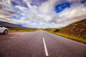 Fototapeta na wymiar Trip or adventure: Abandoned, dramatic road in Scotland, cloudy sky.