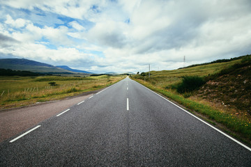 Trip or adventure: Abandoned, dramatic road in Scotland, cloudy sky.
