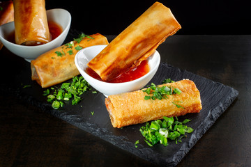 Fried spring rolls on black slate decorated with greens-2.