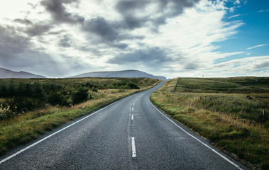 Trip or adventure: Abandoned, dramatic road in Scotland, cloudy sky.