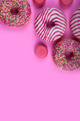 Donuts and macaroons on a pink background.