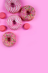 Donuts and macaroons on a pink background.