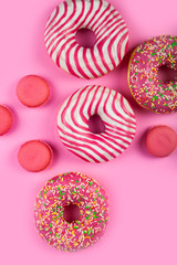 Donuts and macaroons on a pink background.