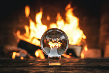 Fire flame reflection in a crystal ball on a table.