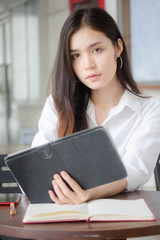 Fototapeta premium Portrait of thai adult student university uniform beautiful girl using her tablet.