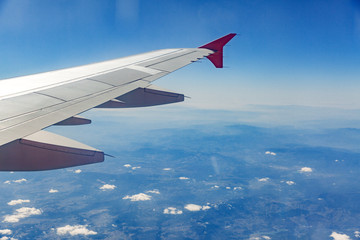 Obraz premium Aircraft wing on the clouds, flies on the city background