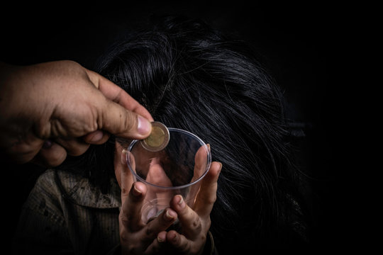 Young and dirty beggar asking hand holding for some money on black background