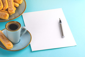 A sheet of white paper is empty on a blue background with an ink pen . Copy space.