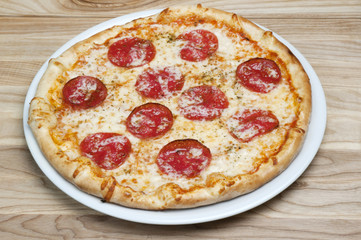 Delicious pizza with cheese and tomatoes on a wood background