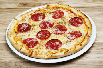 Delicious pizza with cheese and tomatoes on a wood background