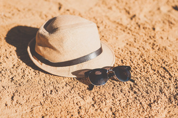 Straw hat and sunglasses on sand beach.